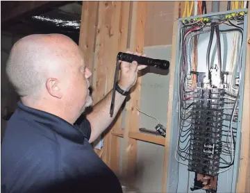  ?? J. Ross Rogers / Rome News-Tribune ?? ABOVE: John Caldwell, owner of WIN Home Inspection in Lindale, looks at the circuit box of a house as part of the inspection process.