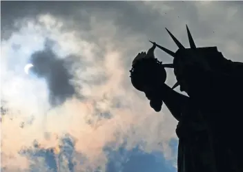  ??  ?? La Estatua de la Libertad fue otro sitio donde el “gran eclipse” se pudo ver y millones de estadounid­enses lo recibieron con aplausos y gritos de alegría.