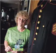  ?? DANNY DAMIANI, USA TODAY NETWORK ?? Beverly Kittoe, Sgt. Brandon Ketchum’s mother, displays his uniform and a photo of herself and both of her sons. Challenged while raising a rebellious Brandon, she sent him at age 14 to live with a father he hardly knew in Des Moines.