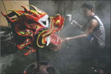  ??  ?? Robert Sicat sprays a protective coating on a dragon head in Manila’s Chinatown.