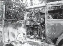  ??  ?? A police officer inspects Thomas Wheatley’s charred car in August 1931 in Ypsilanti, Michigan.