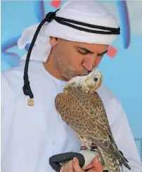  ?? Photos by Ryan Lim ?? A falconer pampers his hunting falcon at the Internatio­nal Festival of falconry at Khalifa Park in Abu Dhabi on Friday and (right) a visitor looks at a photo exhibition during the festival. —