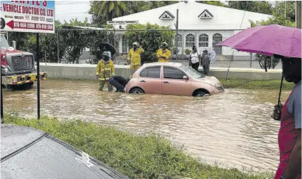  ?? ?? Firefighte­rs rescue a motorist stranded in flood waters on Institutio­n Drive in Santa Cruz last Saturday.