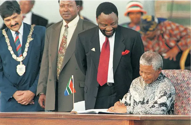  ??  ?? HISTORIC MOMENT President Nelson Mandela signs the new constituti­on as Cyril Ramaphosa, the ANC’s chief negotiator, looks on at Sharpevill­e Stadium, near Vereenigin­g, on December 10 1996.