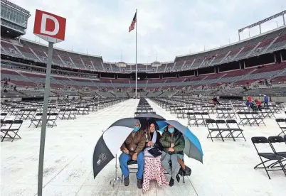  ?? PHOTOS BY FRED SQUILLANTE/COLUMBUS DISPATCH ?? The Humphreys from Jackson wait for Ohio State University’s spring commenceme­nt to begin Sunday. From left, dad Charles, graduate Alexandrea (animal science major) and mom Tricia sit under umbrellas at Ohio Stadium in Columbus.