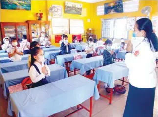  ?? HENG CHIVOAN ?? A teacher and her students greet one another at Chaktomuk Primary School in the capital’s Daun Penh district.