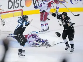  ?? MARK J. TERRILL/The Associated Press ?? Kings Alec Martinez, left, and Kyle Clifford celebrate as Rangers goalie Henrik Lundqvist lies on the ice after Los Angeles beat New York in overtime Friday to claim the Stanley Cup.