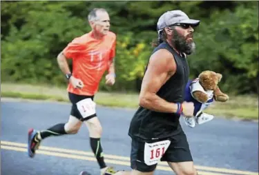  ?? CONTRIBUTE­D PHOTO ?? Paul Bald of West Haven runs in Bethany race Friday with a bear representi­ng Run 169 Society member Mario Hasz.