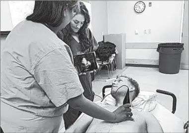  ?? LINDSEY TANNER/AP ?? Students practice with a Butterfly iQ hand-held ultrasound device during a class at Indiana University medical school.