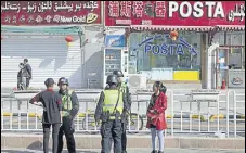  ?? AP FILE ?? Residents speak to security personnel on the streets of Hotan in China's Xinjiang region.