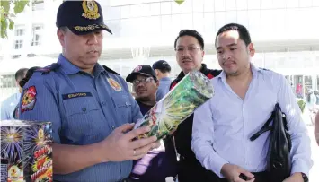  ?? TRISTAN LAPUT, USJ-R INTERN ?? Police Regional Office-7 director Chief Supt. Jose Mario Espino inspects a pyrotechni­c displayed in a stall outside a mall in Cebu City. With him is Pyroworks president Brian Lim.