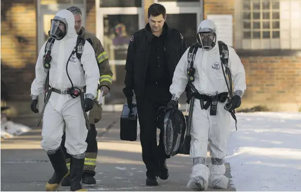  ?? GREG SOUTHAM ?? Firefighte­rs wearing Hazmat suits walk away from Distinctiv­e Employment Counsellin­g Services of Alberta on Monday.