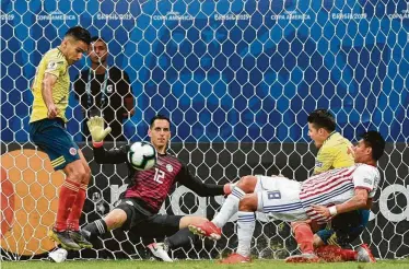  ?? Juan Mabromata / AFP/Getty Images ?? El delantero Radamel Falcao (izq.) y el volante James Rodríguez llegan con peligro hasta la portería de Roberto Fernández (centro) durante el triunfo de Colombia sobre Paraguay en la Copa América.