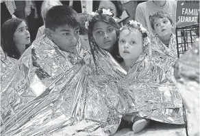  ?? ALEX WONG/GETTY IMAGES ?? Children wrap themselves in Mylar blankets to represent kids separated from their families, during a protest Thursday on Capitol Hill.