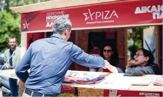  ?? ?? Premier Kyriakos Mitsotakis greets people sitting at a SYRIZA polling booth in the district of Kypseli, central Athens, on May 13, 2023. Both ND and the parties of the opposition have been trying to woo voters away from their political opponents.
