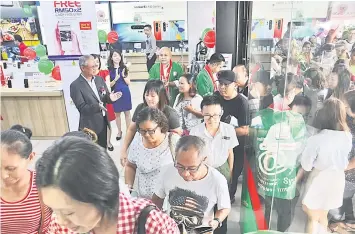  ??  ?? Lim (left, wearing spectacle) welcomes Senheng’s PlusOne members at the Grand Senheng outlet to get items on promotion during the opening ceremony.