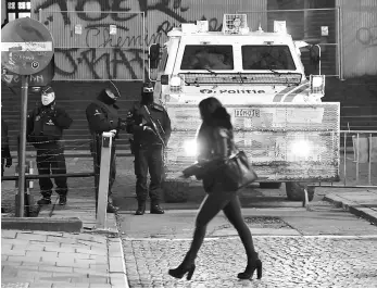  ?? — AFP photo ?? A woman walks past Belgian policemen standing guard at the entrance to the Palais de Justice courthouse in Brussels for the second day of the trial of Abdeslam.