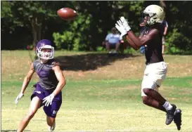  ?? Photos by LARRY GREESON / For the Calhoun Times ?? ( ABOVE) Calhoun’s Jevard Williams (right) goes up to make a catch behind a Gilmer defender on Thursday at passing camp. ( BELOW) Calhoun quarterbac­k Baylon Spector loads up to make a throw on Thursday.