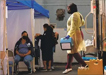  ??  ?? ANA AMADAOR carries a cooler of vaccines Saturday in L.A. Gov. Gavin Newsom says the state will sign a contract with Blue Shield of California to improve data collection and overhaul how doses are allocated.