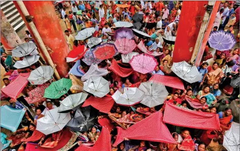  ??  ?? Devotees hold up clothes and umbrellas to receive rice as offerings being distribute­d by a temple authority on the occasion of Annakut festival in Kolkata on Friday. REUTERS