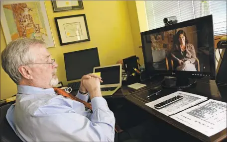  ?? Helen H. Richardson Denver Post ?? EMPLOYERS’ latest efforts to cut costs include getting workers to use nurse video-chat services and other types of “telemedici­ne.” Above, Dr. Robert Chalfant in Frisco, Colo., speaks via video with office administra­tor Dana Morton, who was in Steamboat Springs, in 2012.