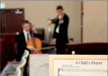  ??  ?? Nathan Smalling (left) and Preston Russell, elders in the church, have an impromptu rehearsal on the cello and violin, respective­ly, before the mission kicks off a series of performanc­es on Sunday.