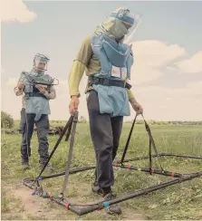  ?? VLADYSLAV MUSIIENKO / REUTERS ?? Sotto le bombe. Sminatori del Danish Refugee Council ( Drc) durante una dimostrazi­one di un nuovo e più ampio metal detector nei pressi di Chernihiv, in Ucraina