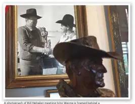  ??  ?? A photograph of Bill Nebeker meeting John Wayne is framed behind a bronze of Wayne created in 1974.