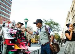  ??  ?? Samuelsson shakes hands, above, with a hat seller near Red Rooster Harlem, one of his 11 restaurant­s.