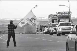  ?? HERALD FILE PHOTOS BY DALE WOODARD ?? A flag waver greets a line up trucks as part of the protest convoy as it arrived in Coutts back in January.