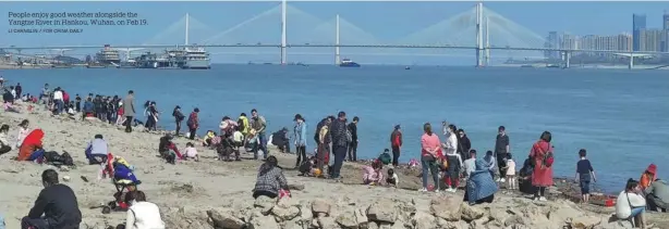  ?? LI CHANGLIN / FOR CHINA DAILY ?? People enjoy good weather alongside the Yangtze River in Hankou, Wuhan, on Feb 19.