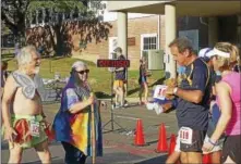  ?? LUIS MAYSONET PHOTO ?? From left: Charlie Merlis (with the wings) looks on as widow Diane Hasz, with the help of a walking stick, is handed a bear by Richard Zbrozek to carry over the finish line in honor of her late husband, Mario Hasz. Katey Baruth is in pink.