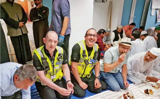  ??  ?? Thin chew line: Officers break their fast at the mosque in Northampto­n, in a photo that provoked criticism from businesses