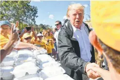  ?? Nicholas Kamm / Getty Images ?? President Donald Trump greets residents beside a table of prepared meals in New Bern, N.C., as he tours areas of pummeled by Hurricane Florence.