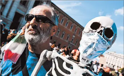  ?? ANDREAS SOLARO/GETTY-AFP ?? A protester holds a reproducti­on of a human skeleton Saturday in Rome. The mask says, “I did not die of coronaviru­s but of hunger.”