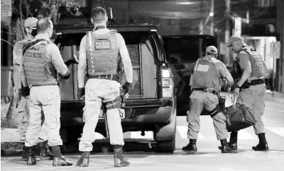  ?? AP ?? Military police officers carry a bag filled with money left behind by armed bank robbers in Criciuma, Santa Catarina state, Brazil, on Tuesday.