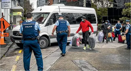  ?? DAVID WHITE/STUFF ?? 501 deportees walk past a heavy police presence as they settle in for enforced Covid-19 quarantine at the Ramada Hotel in Auckland in July 2020.