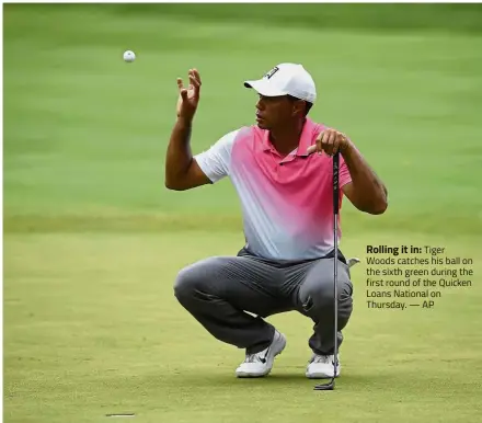  ?? — AP ?? Rolling it in: Tiger Woods catches his ball on the sixth green during the first round of the Quicken Loans National on Thursday.