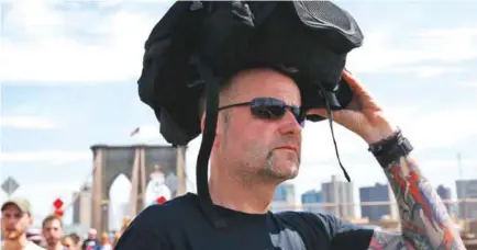  ??  ?? NEW YORK: In this July 24, 2016, file photo German tourist Guido Weber of Hanover uses his backpack to cover his head against the hot afternoon sun after forgetting to wear his hat as he walks across the Brooklyn Bridge. — AP