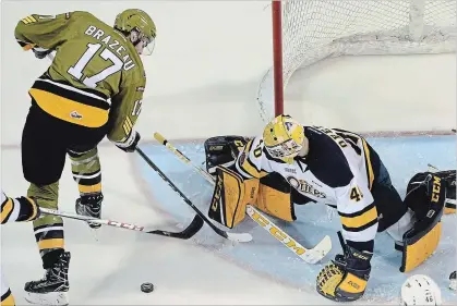  ?? JACK HANRAHAN THE ASSOCIATED PRESS ?? Erie Otters goalie Anand Oberoi makes a save on North Bay Battalion’s Justin Brazeau during an OHL game in December 2017 at Erie Insurance Arena in Erie, Pa. The league’s current top scorer, he remains undrafted, but still hopeful of making the pros.