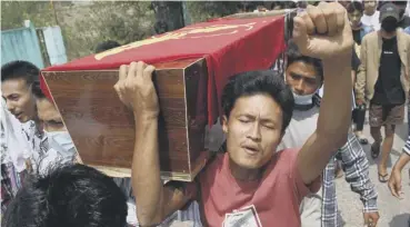  ??  ?? 0 A mourner gestures while carrying the coffin of a dead protester