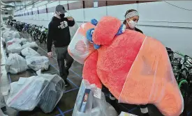  ?? BILL LACKEY/STAFF ?? Springfiel­d Salvation Army volunteers collected bags of toys and bicycles from the sea of plastic bags and rows of bikes during the Army’s Christmas toy distributi­on for needy families Thursday at the Clark County Fairground­s.