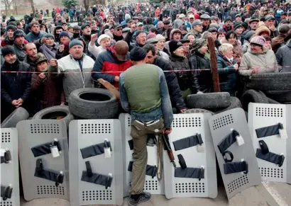  ?? AFP ?? Pro-Russian protesters shout slogans as an armed activist guards a police station in the eastern Ukrainian city of Slavyansk after it was seized by a few dozen gunmen on Saturday. —