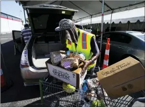  ?? AP PHOTO/ROSS D. FRANKLIN ?? A volunteer fills up a vehicle with food boxes at the St. Mary’s Food Bank on June 29in Phoenix.