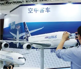  ??  ?? A visitor takes a photo of a model of an Airbus A380 plane at Aviation Expo China 2017 in Beijing. Chinese airlines could buy as many as 100 of the planes over the next five years. (Reuters)