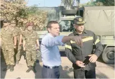  ?? — Reuters ?? Greek Prime Minister Alexis Tsipras speaks with a firefighte­r officer as he visits the village of Mati, following a wildfire near Athens.