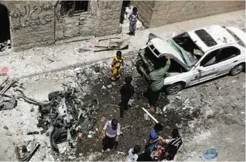  ?? AP ?? Scene of carnage People stand amid wreckage of a car at the site of a car bomb attack in Sana’a yesterday.