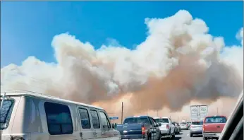  ?? The Associated Press ?? Smoke from the Tunnel Fire fills the sky in Doney Park, outside Flagstaff, Ariz., on Tuesday. The wildfire doubled in size overnight after tearing through two-dozen structures and forcing the evacuation of more than 700 homes.