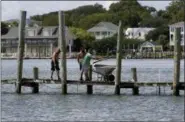  ?? TOM COPELAND — THE ASSOCIATED PRESS ?? From left, Josh Clappsy, Blake Price, and JB Phillips remove boards from a dock in hopes to save it from rising waters in Swansboro, N.C., Tuesday. Florence exploded into a potentiall­y catastroph­ic hurricane Monday as it closed in on North and South Carolina, carrying winds up to 140 mph (220 kph) and water that could wreak havoc over a wide stretch of the eastern United States later this week.