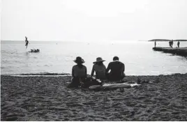  ?? YORGOS KARAHALIS/AP ?? People sit on a beach Tuesday in Kavouri, near Athens, Greece.